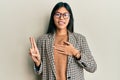 Young chinese woman wearing business style and glasses smiling swearing with hand on chest and fingers up, making a loyalty