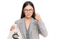 Young chinese woman wearing business suit holding dollars bag annoyed and frustrated shouting with anger, yelling crazy with anger Royalty Free Stock Photo