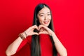 Young chinese woman wearing casual clothes smiling in love doing heart symbol shape with hands Royalty Free Stock Photo