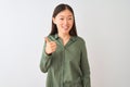 Young chinese woman wearing casual green shirt standing over isolated white background doing happy thumbs up gesture with hand Royalty Free Stock Photo