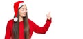 Young chinese woman wearing christmas hat looking proud, smiling doing thumbs up gesture to the side Royalty Free Stock Photo
