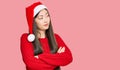 Young chinese woman wearing christmas hat looking to the side with arms crossed convinced and confident Royalty Free Stock Photo