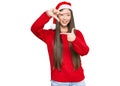 Young chinese woman wearing christmas hat smiling making frame with hands and fingers with happy face Royalty Free Stock Photo