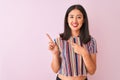 Young chinese woman wearing colorful striped t-shirt standing over isolated pink background smiling and looking at the camera Royalty Free Stock Photo