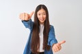 Young chinese woman wearing denim shirt standing over isolated white background approving doing positive gesture with hand, thumbs Royalty Free Stock Photo