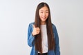 Young chinese woman wearing denim shirt standing over isolated white background doing happy thumbs up gesture with hand Royalty Free Stock Photo
