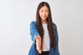 Young chinese woman wearing denim shirt standing over isolated white background smiling friendly offering handshake as greeting Royalty Free Stock Photo