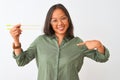 Young chinese woman wearing glasses holding chopsticks over isolated white background with surprise face pointing finger to