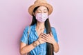 Young chinese woman wearing medical mask on summer smiling with hands on chest, eyes closed with grateful gesture on face Royalty Free Stock Photo