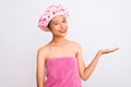 Young chinese woman wearing shower towel and cap bath over isolated white background smiling cheerful presenting and pointing with Royalty Free Stock Photo