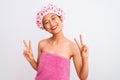 Young chinese woman wearing shower towel and cap bath over isolated white background smiling looking to the camera showing fingers Royalty Free Stock Photo