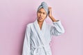 Young chinese woman wearing shower towel cap and bathrobe confuse and wonder about question