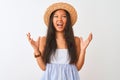Young chinese woman wearing striped dress and hat standing over isolated white background crazy and mad shouting and yelling with Royalty Free Stock Photo