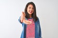 Young chinese woman wearing striped t-shirt and denim shirt over isolated white background smiling friendly offering handshake as Royalty Free Stock Photo