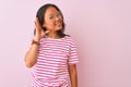 Young chinese woman wearing striped t-shirt and glasses over isolated pink background smiling with hand over ear listening an Royalty Free Stock Photo