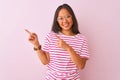 Young chinese woman wearing striped t-shirt and glasses over isolated pink background smiling and looking at the camera pointing Royalty Free Stock Photo