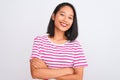 Young chinese woman wearing striped t-shirt standing over isolated white background happy face smiling with crossed arms looking Royalty Free Stock Photo