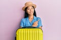 Young chinese woman wearing summer hat and holding cabin bag smiling cheerful pointing with hand and finger up to the side Royalty Free Stock Photo