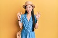Young chinese woman wearing summer hat showing and pointing up with fingers number nine while smiling confident and happy Royalty Free Stock Photo