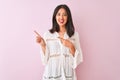 Young chinese woman wearing summer shirt standing over isolated pink background smiling and looking at the camera pointing with Royalty Free Stock Photo