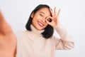 Young chinese woman wearing turtleneck sweater make selfie over isolated white background with happy face smiling doing ok sign Royalty Free Stock Photo
