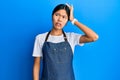 Young chinese woman wearing waiter apron confuse and wonder about question