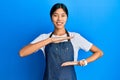 Young chinese woman wearing waiter apron gesturing with hands showing big and large size sign, measure symbol Royalty Free Stock Photo