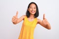 Young chinese woman wearing yellow casual t-shirt standing over isolated white background approving doing positive gesture with Royalty Free Stock Photo