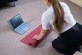 Young chubby woman folds sports mat after online fitness class