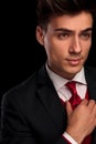 Young classy male in black suit fixing his tie