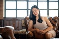 Young classy Asian woman sitting on vintage sofa in the luxury and fancy living room Royalty Free Stock Photo