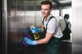 young cleaning company worker cleaning elevator and smiling at camera Royalty Free Stock Photo