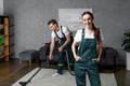 young cleaning company workers using vacuum cleaner and smiling