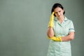 Young cleaning woman wearing a green shirt and yellow gloves has headache Royalty Free Stock Photo