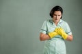 Young cleaning woman wearing a green shirt and yellow gloves suffering heart ache or breast pain, cardiac problems Royalty Free Stock Photo