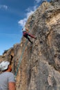 Young climber is descended from the rock wall she has just climbed while her boyfriend belays her from below