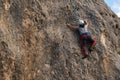 Young climber girl with all the climbing equipment looks for the best route on a rock wall in nature Royalty Free Stock Photo