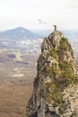 A young climber throws a rope into the abyss from the top of a steep cliff against the backdrop of the city and the