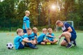 Young coach teaches little children the strategy of playing on football field.