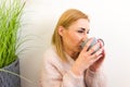 Young cold woman wearing warm sweater drinking hot tea in winter