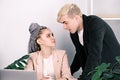 Young colleagues man and woman flirting at work. Woman sitting at desk in office looks into the eyes of man leaning over Royalty Free Stock Photo