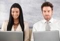 Young colleagues working on laptop smiling