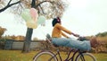 Young colored woman riding a bike playfully raising legs up in autumn park