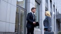 Young company employee talking to strict female boss outside office building