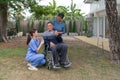 Young compassionate nurse is providing assistance to an elderly man seated in a wheelchair. The nurse is attentive and engaging,