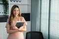 Young competent office lady, intern, secretary holding a log in office room.