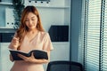 Young competent office lady, intern, secretary holding a log in office room.