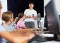 Young computer science teacher standing near an interactive whiteboard tells new material to teenage students in school Royalty Free Stock Photo