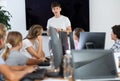 Young computer science teacher standing near an interactive whiteboard tells new material to teenage students in school Royalty Free Stock Photo