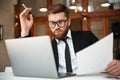 Young concentrated bearded businessman in formalwear looking at